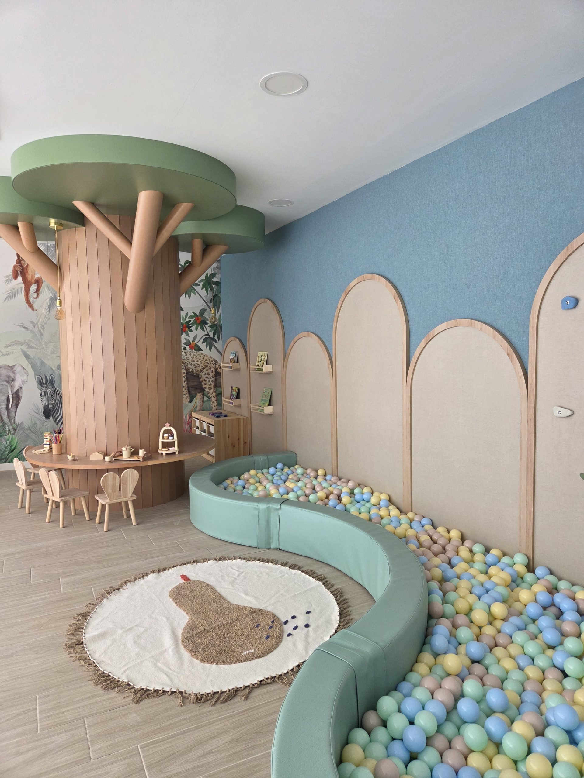Árbol de madera a medida en la ludoteca, con mesa redonda y piscina de bolas