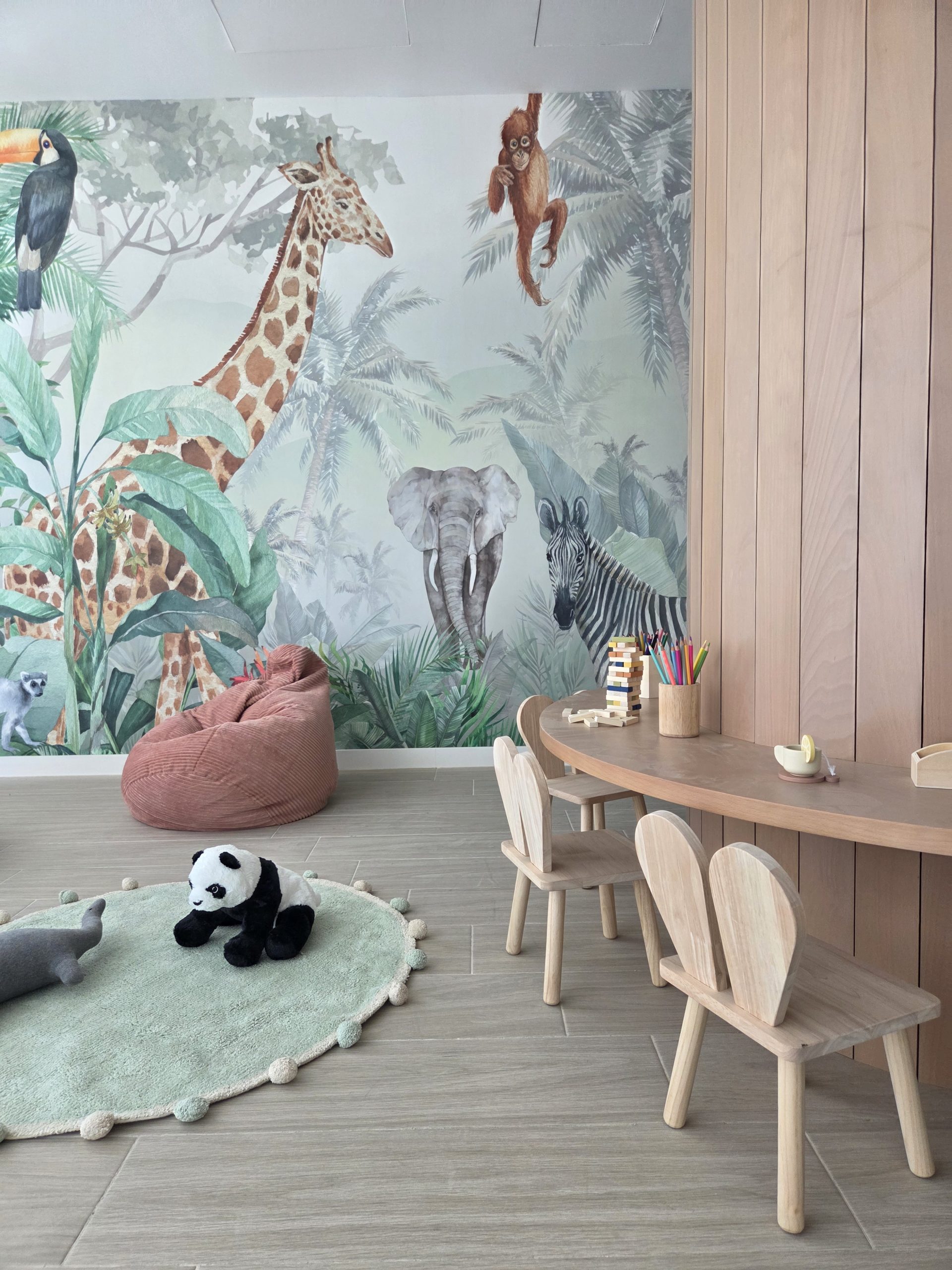 Rincón de lectura de la ludoteca con mural de selva junto al árbol