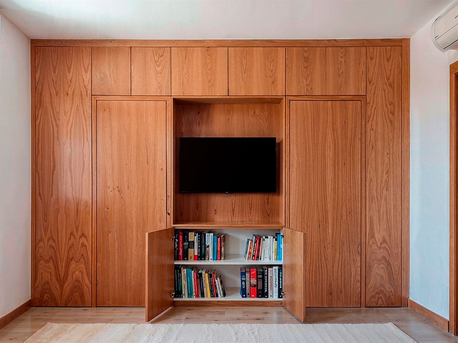 Armario de madera con las puertas de la librería abiertas mostrando las baldas con libros