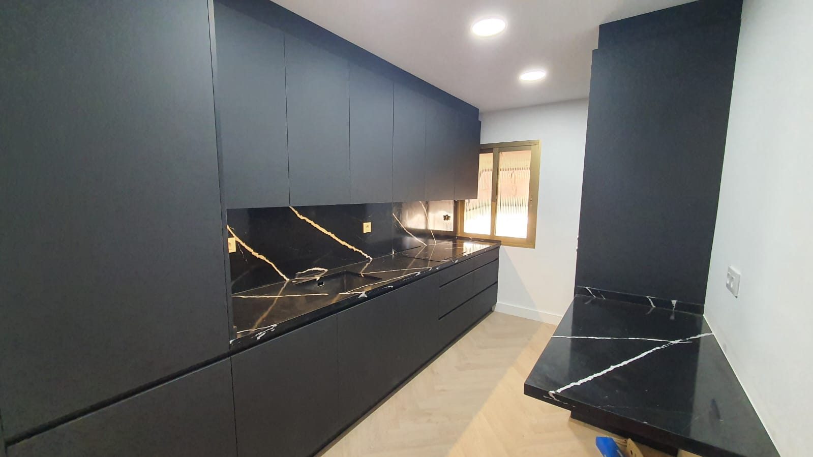 Cocina a medida negra con encimera de mármol Sahara Noir, foto de obra