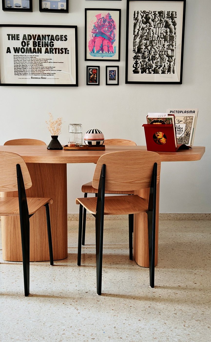 Mesa de forma libre en el salón, con sillas Prouvé y cuadros en la pared