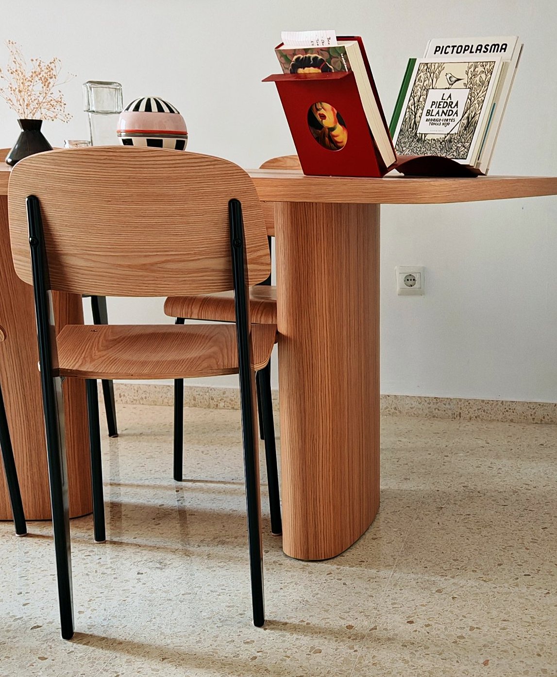 Lateral de la mesa de roble con libros, una silla y la pata