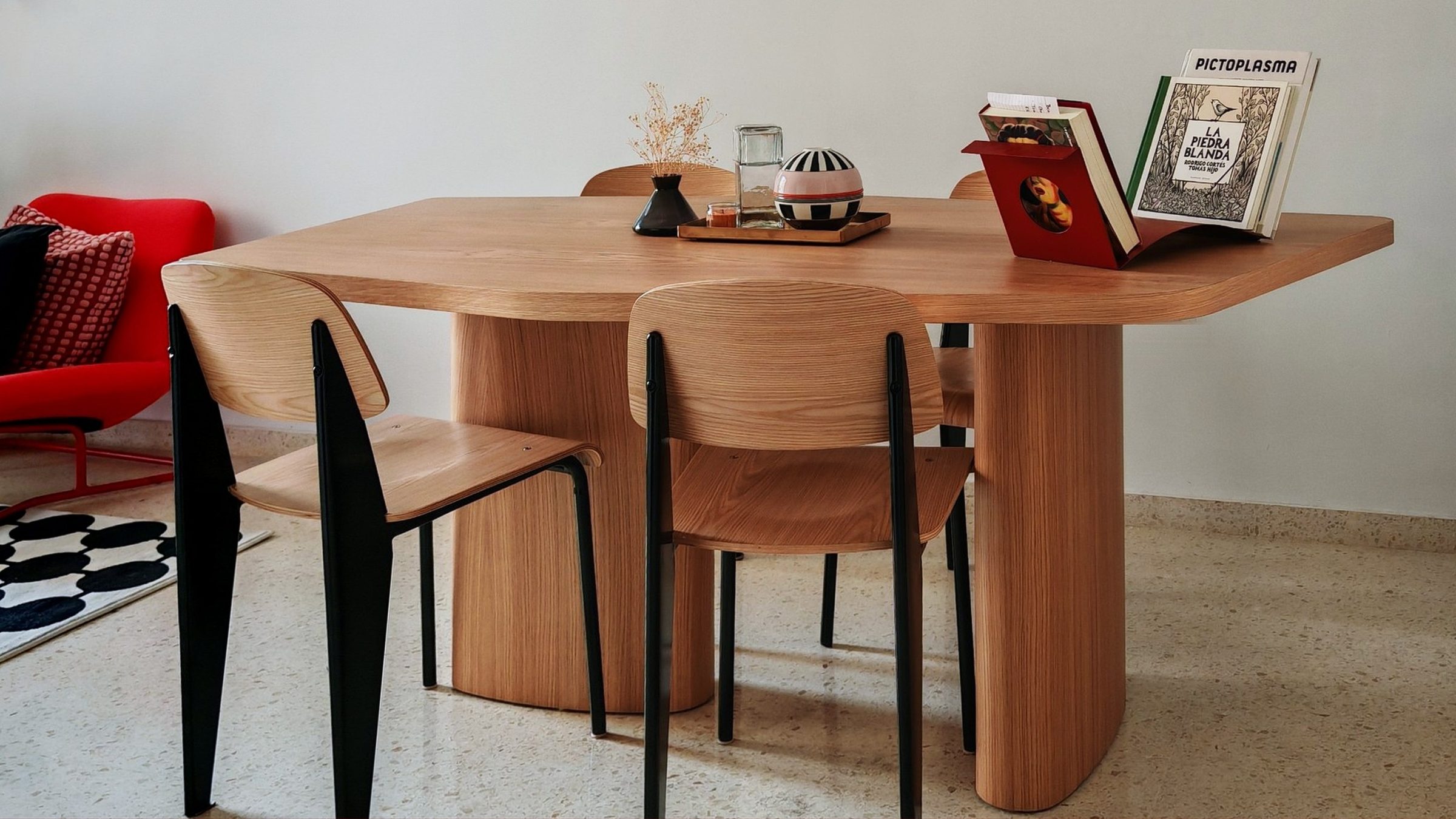 Mesa de comedor de forma libre en roble con libros y sillas Prouvé en el salón