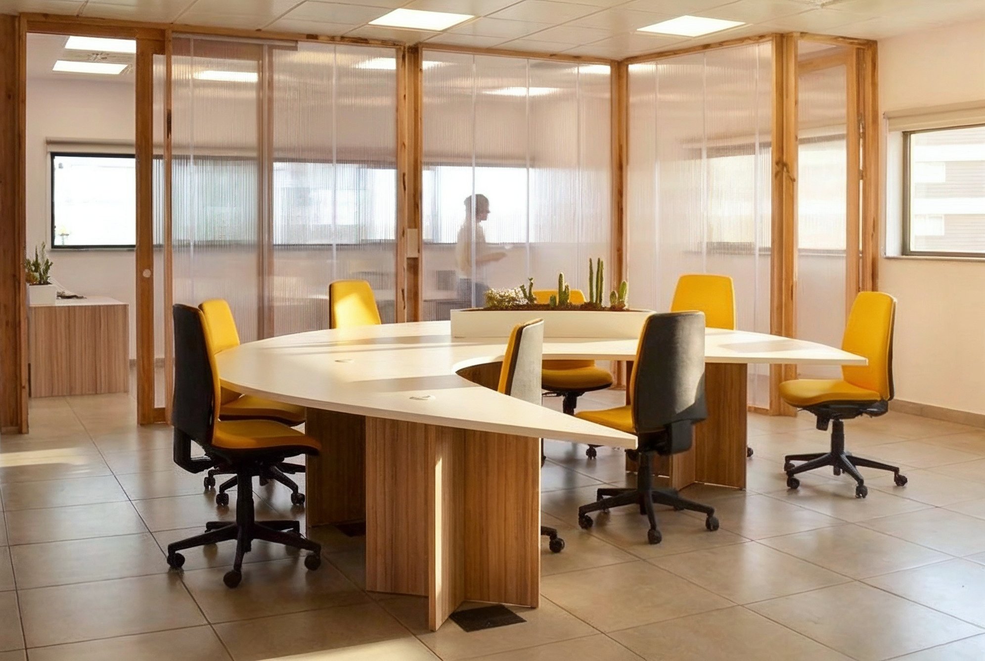 Mesa curva de trabajo compartido junto a las mamparas de madera