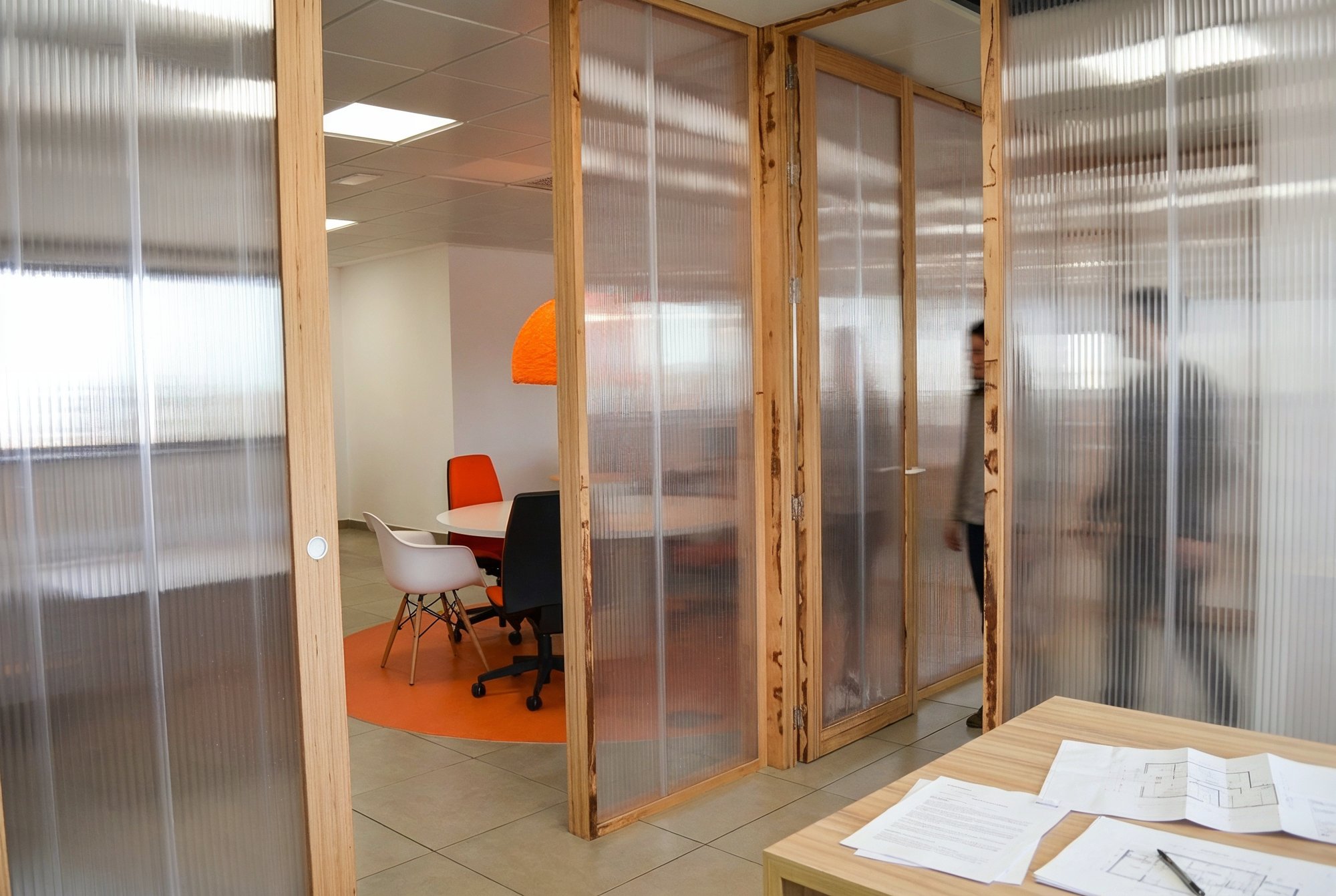 Puerta corredera de mampara con montantes de madera y paneles translúcidos