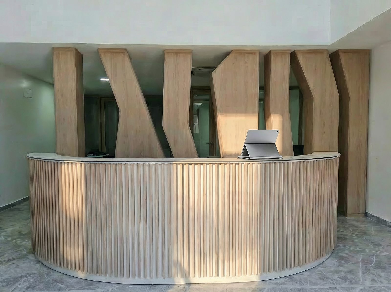 Mostrador de recepción a medida con celosía de madera al fondo, imagen final cuidada